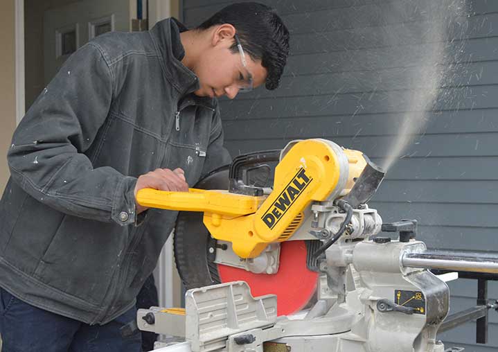 Junior Gonzalo Mora saws a piece of molding for a Habitat for Humanity house on Gold Avenue NW 