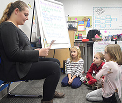 Freshman Mackayla Korreck reads to second-graders Finley Terpstra, Rosie Feldpausch and Josie Pell