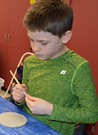 Second-grader Noah Leija envisions a pattern to carve into the wet clay 