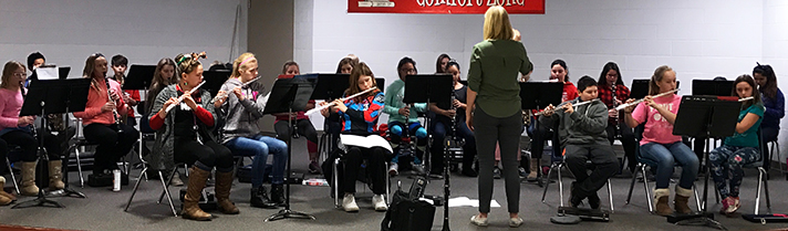 An assistant from Grand Valley State University works with the Kent City woodwind section on their holiday concert music 