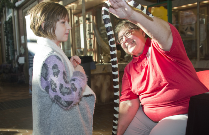 Cecelia Braun, a first-grader at Wealthy Elementary, looks at Cali the California kingsnake while Jackie Fazekas from John Ball Zoo school stretches out the snake to show it is as long as Cecelia is tall. Said Cecelia, “I think it is really cool to get that close to a snake. I’ve been really close to a dragonfly too”