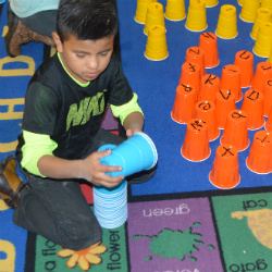 Daniel Montes and other children play a memory game using cups 