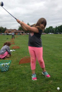 A student perfects her swing in a First Tee golf lesson