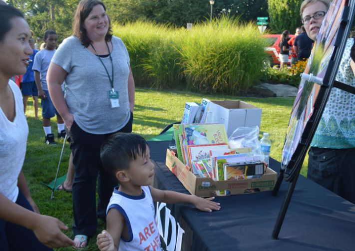 Siang Lian, a Young Fives student, spins a wheel for a prize with mom, Ngun Tint