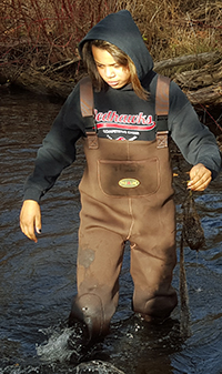 Cedar Springs High School freshman Ebonye Hunter searches Cedar Creek for leaf packs placed in mid-October for a biology experiment to research water quality