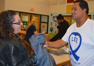 Jaime Ramirez hands a coat to a parent at the recent coat drive