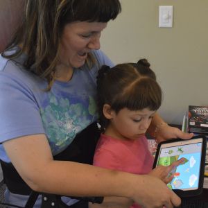 Nora Yarrington helps her daughter Cheyenne match shapes on an iPad