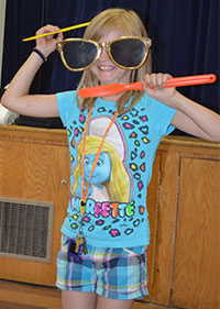 West Kelloggsville Elementary third-grader Thaila Spencer works on combing her hair and brushing her teeth at the same time during the magic show