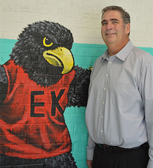 Principal John Keenoy stands next to Freddy the Falcon, which stands at the end of mural