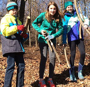 Students Ryan Alexander, Hailey Castor and Ava Mataj remove logs and branches after cutting autumn olive