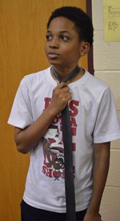 Sixth-grader Jayson Featherstone adjusts his tie