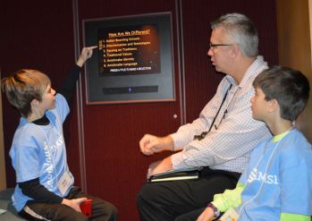 Nick Williams, left, and Zach Kistler watch videos about Native Americans with Zach’s father, David Kistler