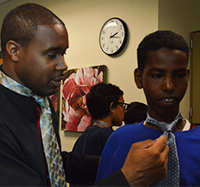 Jermale Eddie, employment and education specialist for Grand Rapids Urban League. helps Crestwood Middle School student Nur Nur tie a tie