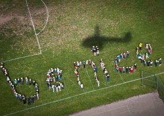 A shadow of the helicopter is cast above Grand Rapids Public Schools Riverside Middle School students' be nice formation 