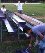 Troop members paint bleachers, part of improving the ball diamond