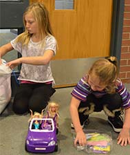 Kim Fisk's daughters Kendell, left, and Lonnitta check out toys and books donated by Cedar Trails Elementary School