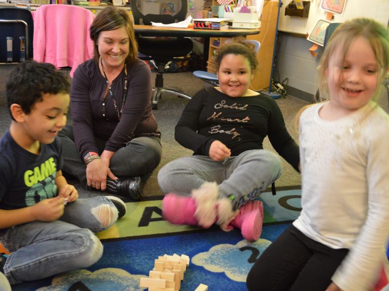 Teacher Jennifer Blackburn joins the fun with her students as a Jenga tower falls during indoor recess