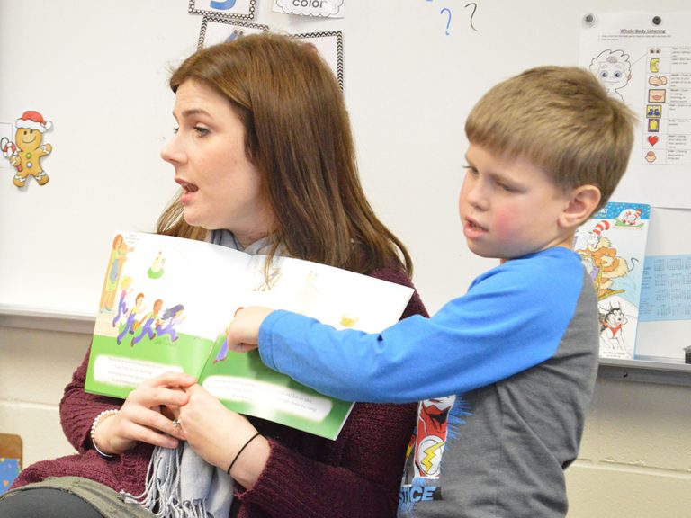 Katee Aubil, speech language pathologist, reads a book about anxiety as part of Social Thinking, with a little help from kindergartner Drake VanLente