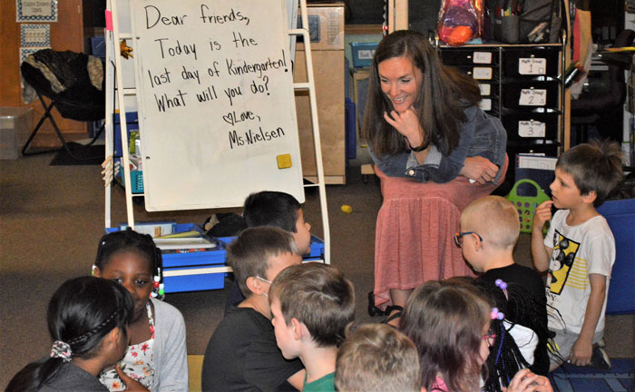 Teacher Stephanie Nielsen leans in to listen as one of her students shares his plans for the summer 