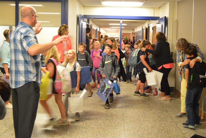 Appleview Principal Mike Birely salutes third-graders who followed their older schoolmates through the hallways 