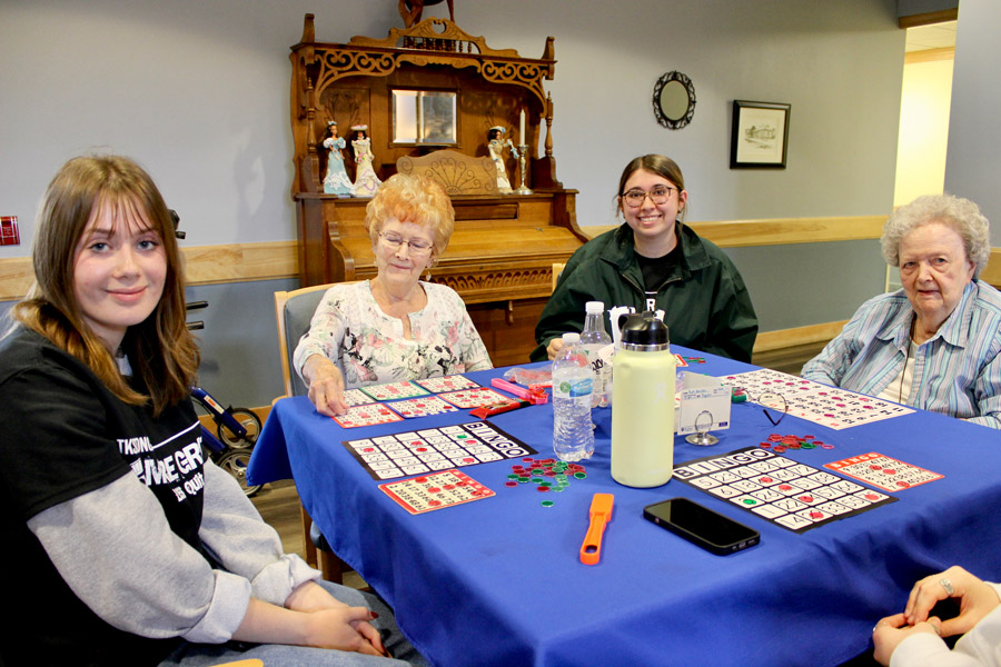 Senior Mia Dickman, second from right, spends her morning at Carveth Village, an assisted-living facility in Middleville, because she served there last year and enjoys hanging out with residents. Also pictured is senior Kelly Lambert, left