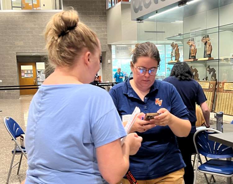 Cassie Groters, Kelloggsville network technician and head of marketing and communications, right, helps a parent get set up with the ParentVue app