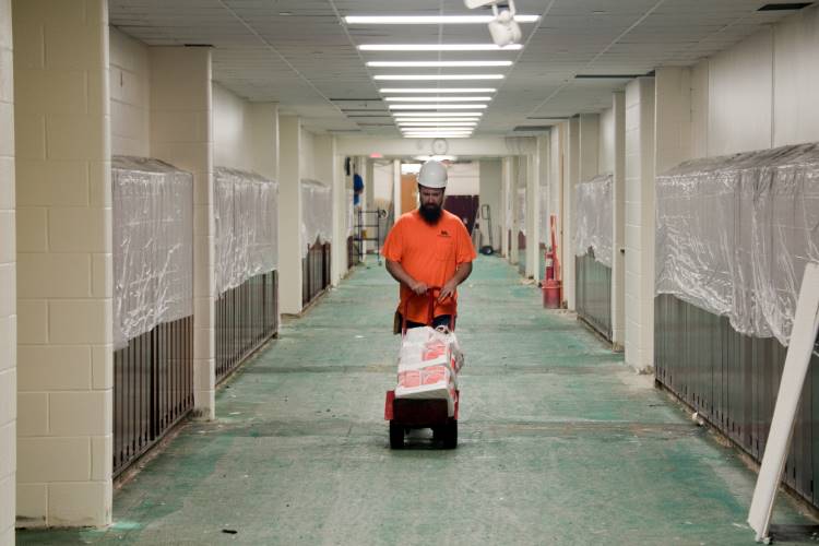 A worker delivers paint to the painters working on the building
