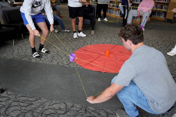 Charley Vickers’ students were given pieces of string and rubber bands to build a system to pick up and dump a plastic cup filled with corn kernels
