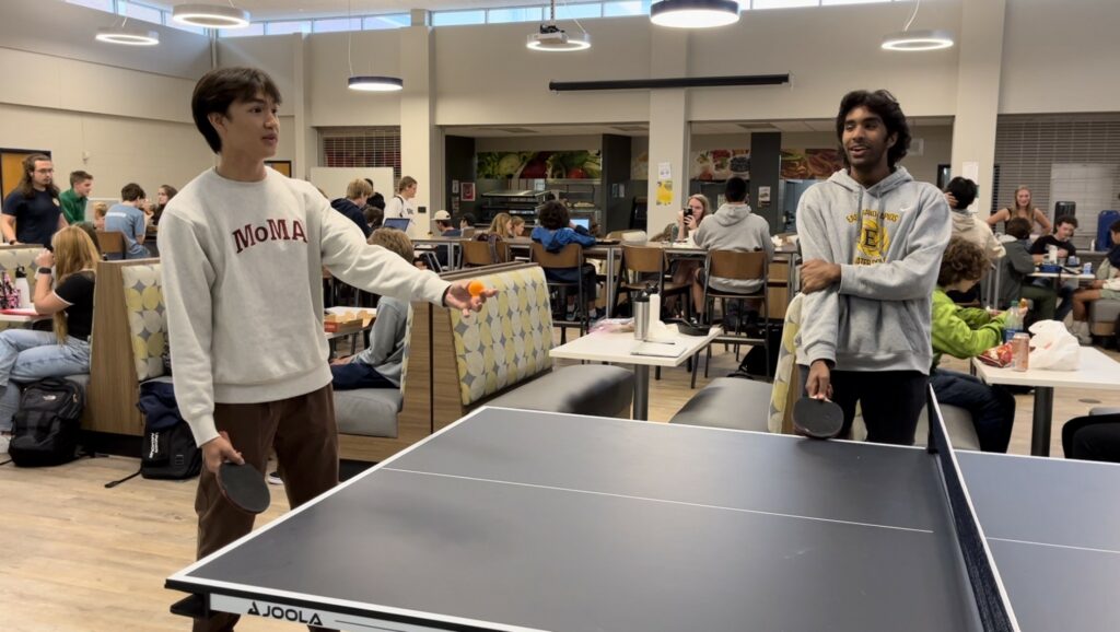 Max Fechtner readies a serve while Harsh Nigam looks on
