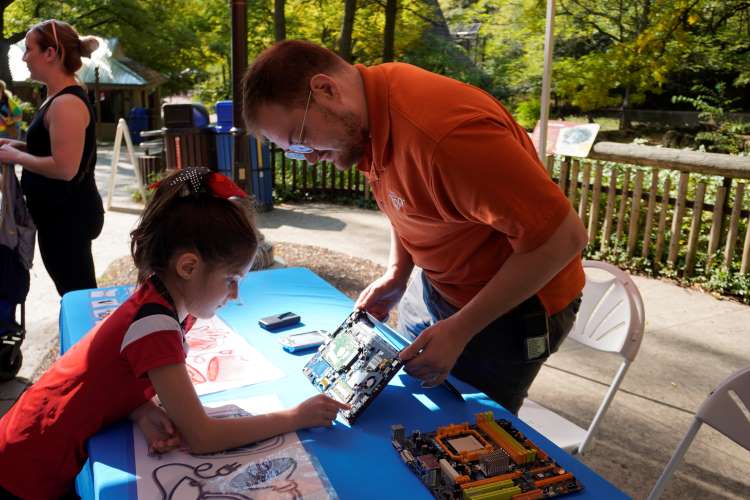 East Oakview Elementary first-grader Reagan Trevino looks over a computer motherboard with Sydney Tripp, John Ball Zoo IT solutions engineer 
