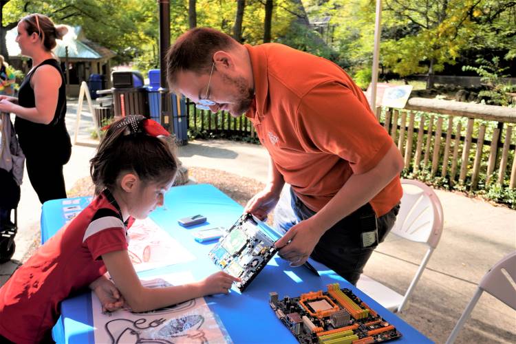 East Oakview Elementary first-grader Reagan Trevino looks over a computer motherboard with Sydney Tripp, John Ball Zoo IT solutions engineer