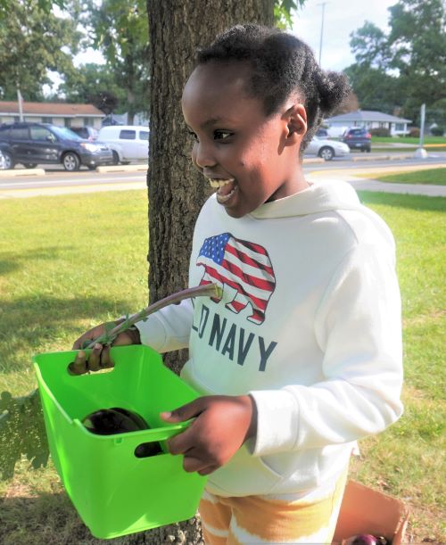 With a big eggplant in her bin, Mutoni Nsanabandi grins big
