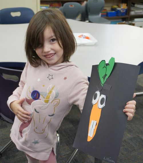 Little girl with a paper carrot that has a scary face