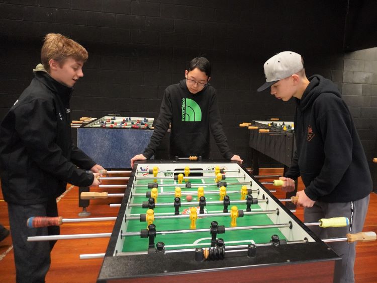 Three boys playing foosball