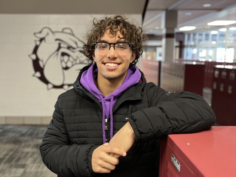 A high school senior poses at his school