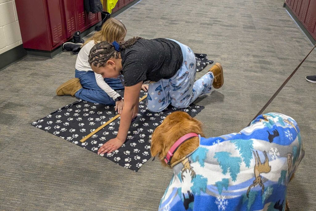 Children measure fabric laid on the floor