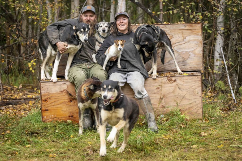 A man and woman pose with many dogs