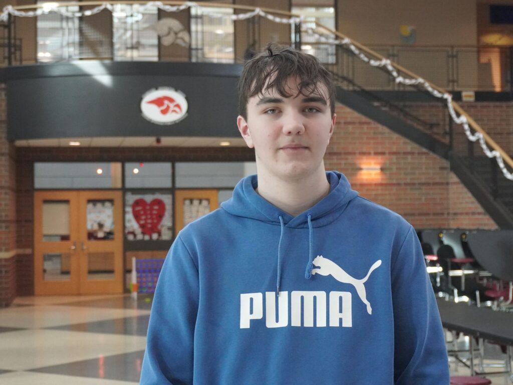 A student in a blue sweatshirt stands in the cafeteria of Cedar Springs Middle School