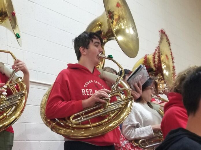 A middle school student in a red sweatshirt plays the tuba
