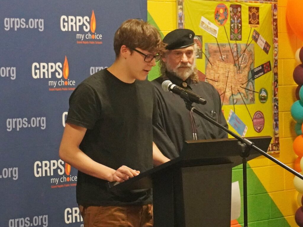 A male student and his parent stand at a podium.